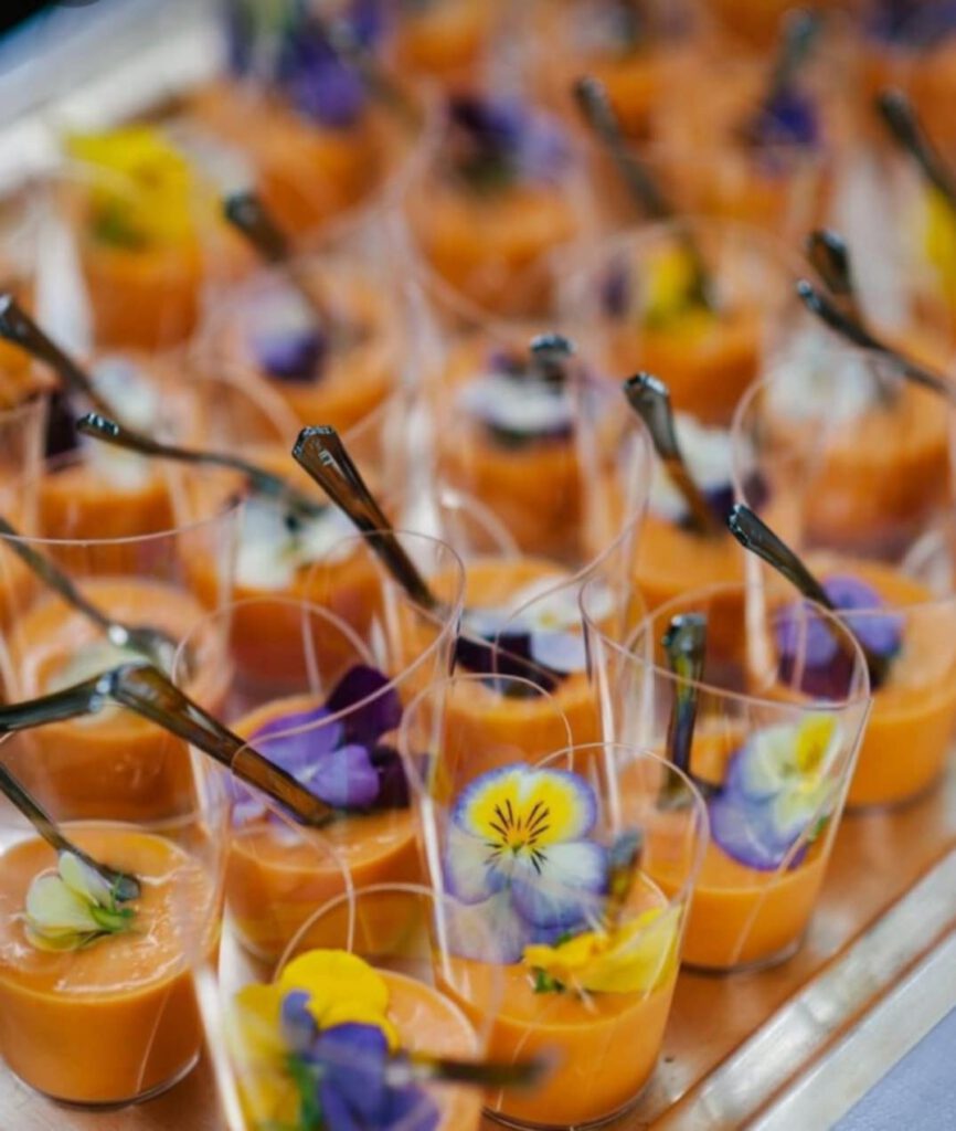 Verrines apéritives colorées à base de carottes et garnies de fleurs comestibles.